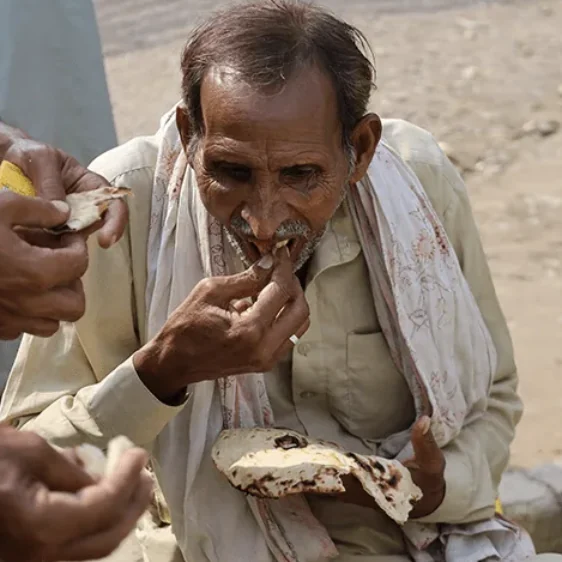 An elder eats fresh bread at a Quba food distribution